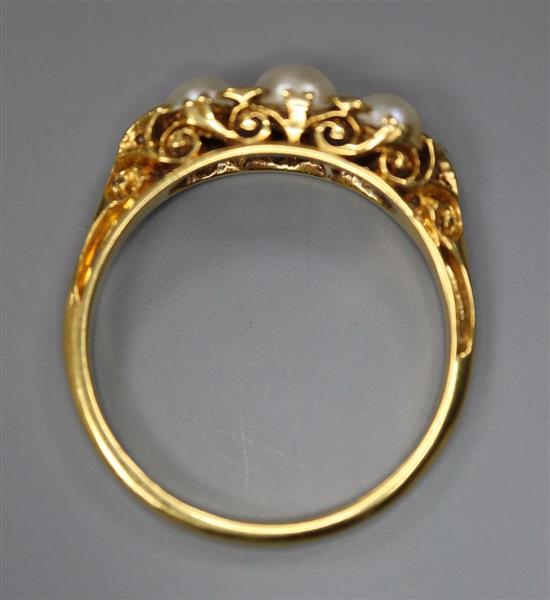 An early 20th century yellow metal and three stone split pearl set half hoop ring, with diamond chip spacers, size P,